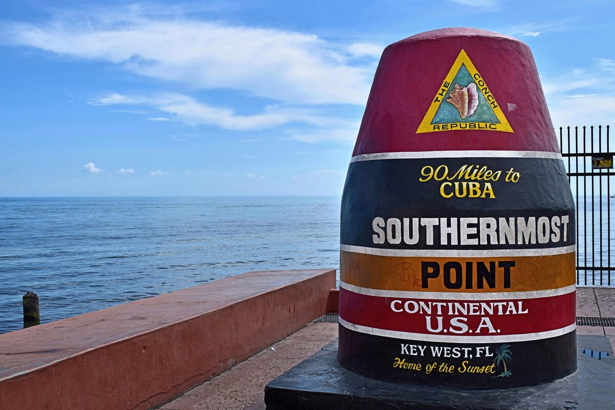 The painted Southernmost Point buoy in Key West, marked 90 Miles to Cuba, with the sea behind it