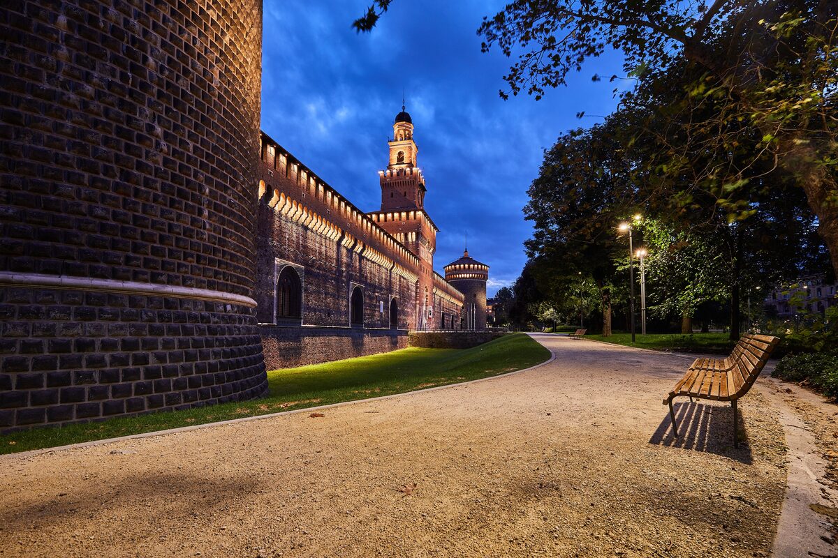 The brick castle wall and tower at dusk, seen from a park path