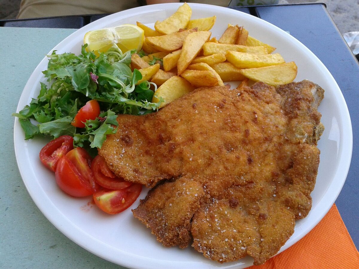 A breaded cutlet with fries and a tomato salad