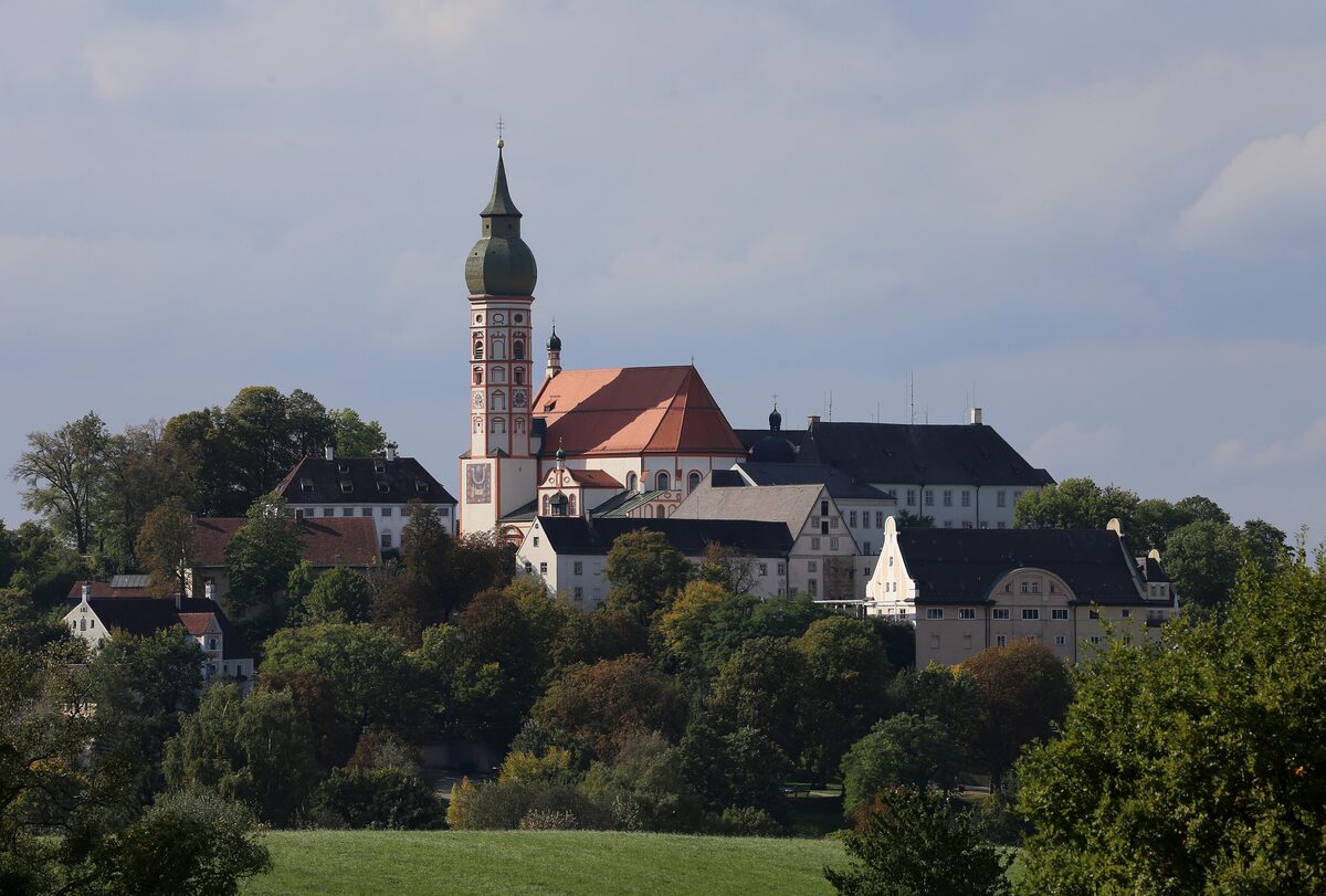 Andechs Monastery with its onion-domed church tower on a wooded hill above green fields