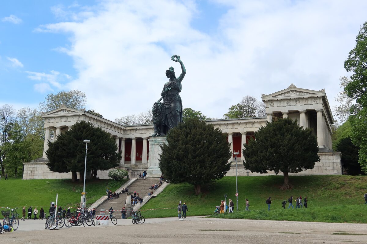 The bronze Bavaria statue on its pedestal in front of the colonnaded Ruhmeshalle, with people on the lawn