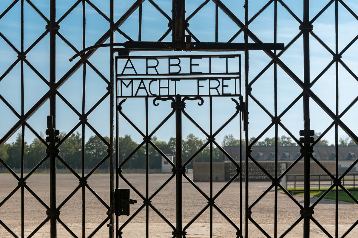 The iron entrance gate of the Dachau Memorial Site with its inscription, looking onto the empty roll-call square
