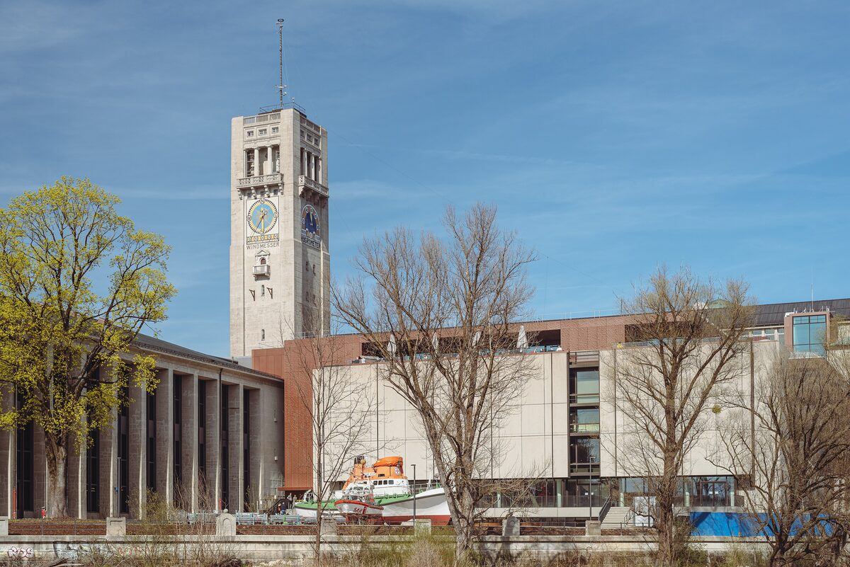 The clock tower and long front of the Deutsches Museum on its island in the Isar, with a ship on display