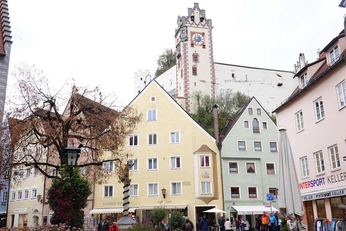 Colorful house fronts on Reichenstraße in Füssen, with the tower of the High Castle behind them
