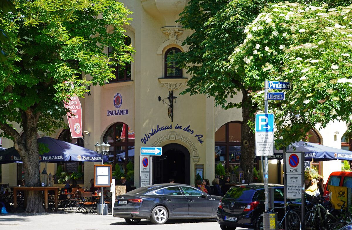 The entrance of the Wirtshaus in der Au on Lilienstraße, with parasols and trees in front