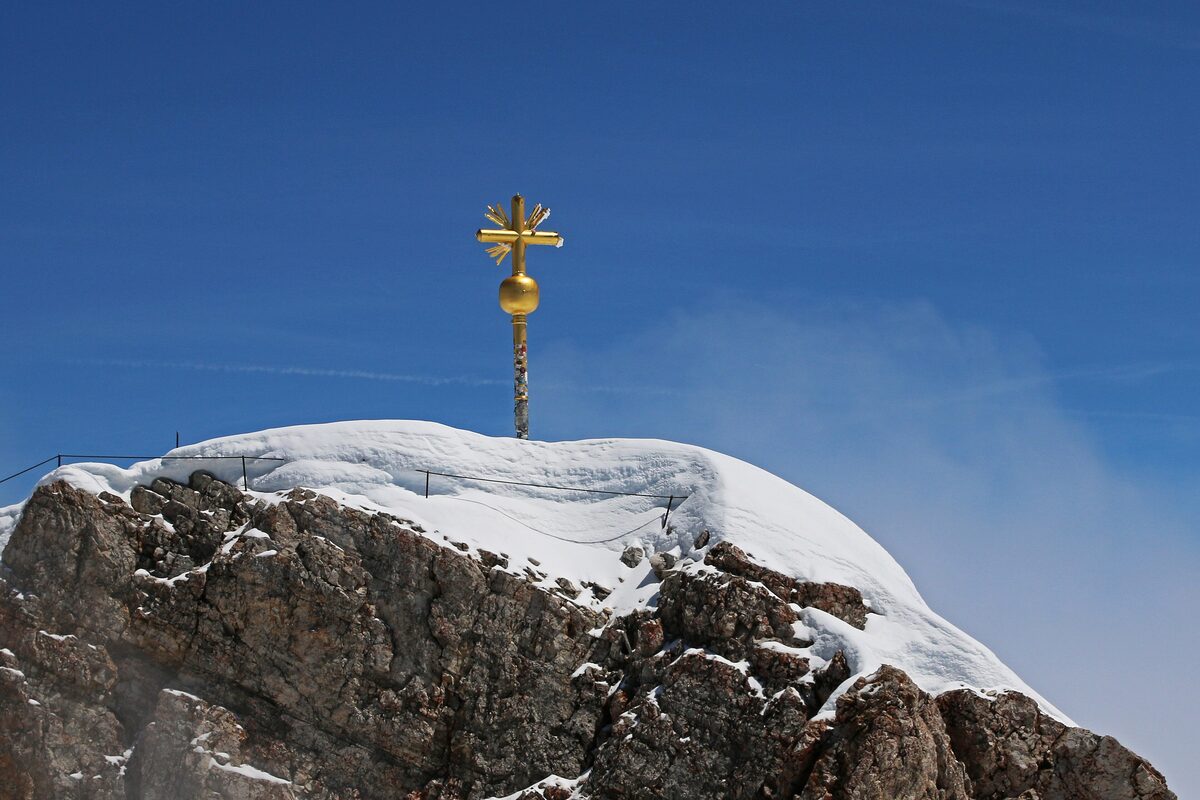 The golden summit cross on the snow-capped rocky top of the Zugspitze