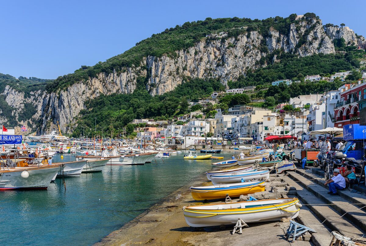 Colorful boats pulled up on the waterfront at Marina Grande on Capri, below green cliffs and white houses