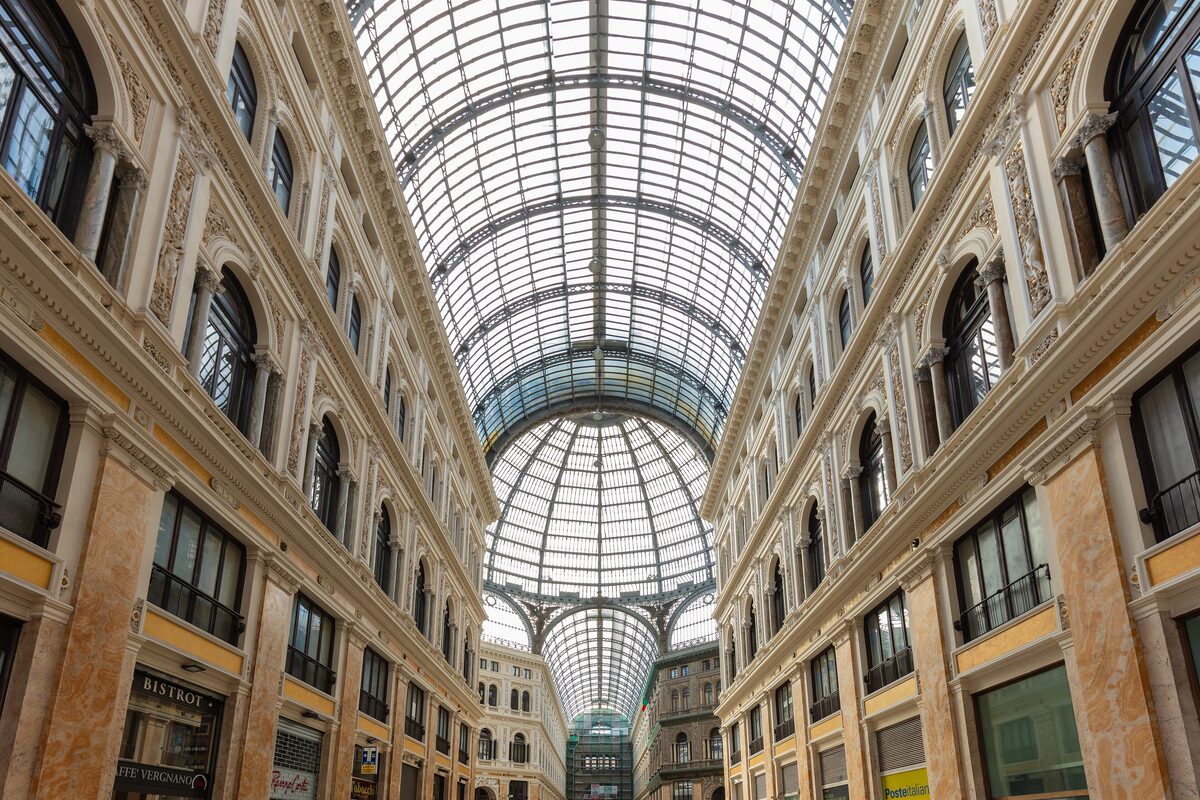 Inside the Galleria Umberto I, a tall shopping arcade with ornate cream facades under a glass and iron roof