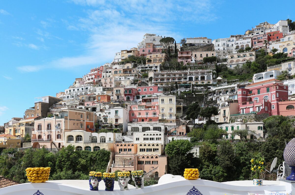 The pastel houses of Positano stacked up a steep green hillside above the sea