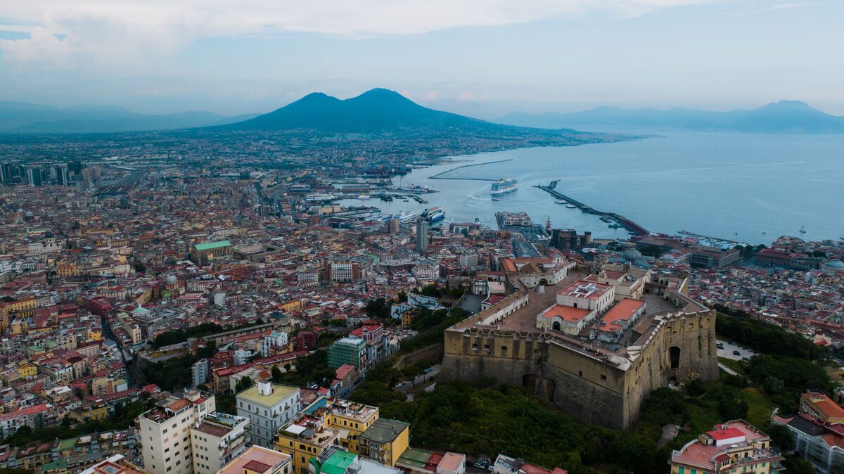 Aerial view of the star-shaped Castel Sant'Elmo on the hill above Naples, with the city, the port and Vesuvius across the bay behind