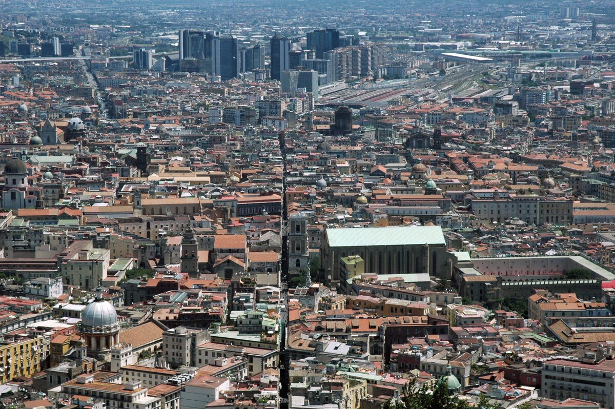 View from above of the old center of Naples, cut in two by the long straight line of Spaccanapoli, with the towers of the business district behind