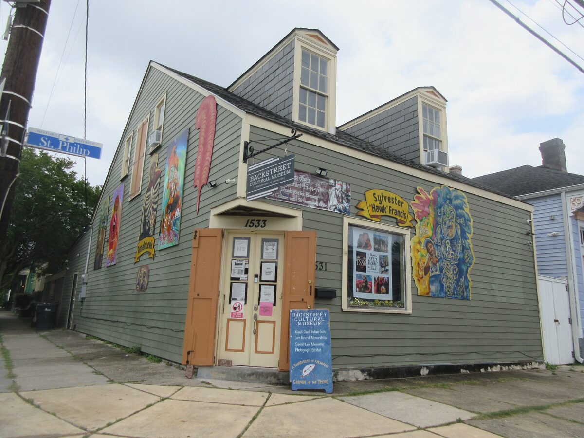 The green wooden corner house of the Backstreet Cultural Museum on St. Philip Street, its side wall covered in colorful murals