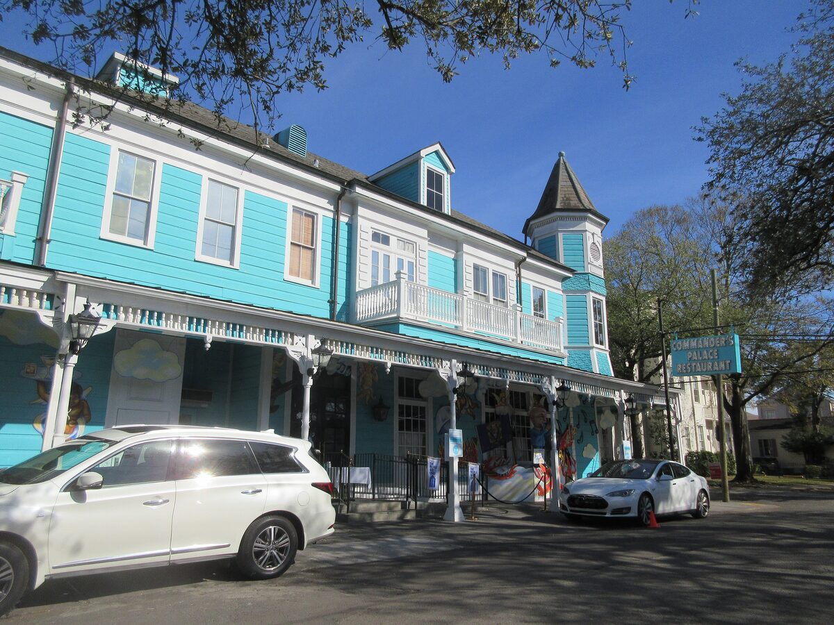 The turquoise Victorian corner building of Commander's Palace with a striped awning and a turret