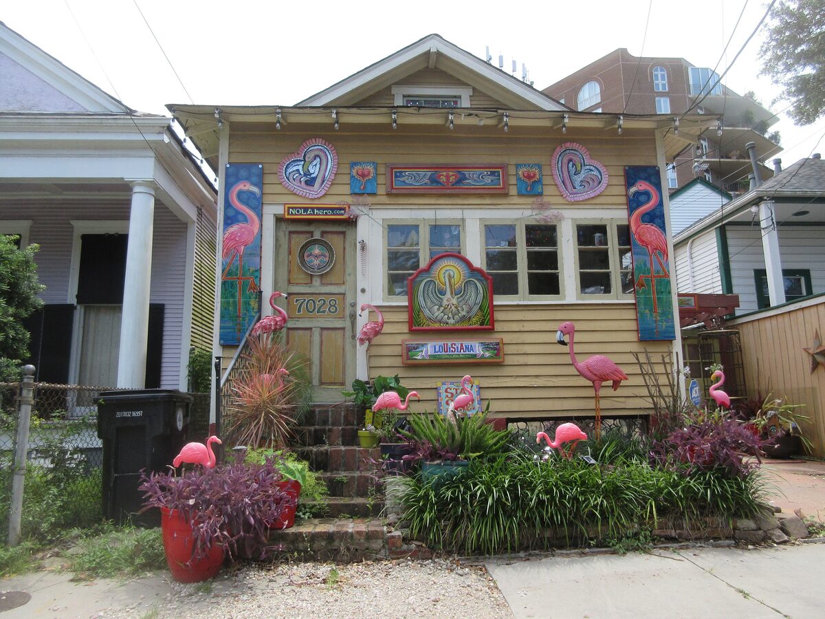 The Flamingo House on Upper Magazine Street, a yellow cottage covered in painted flamingos and a garden of bright plants