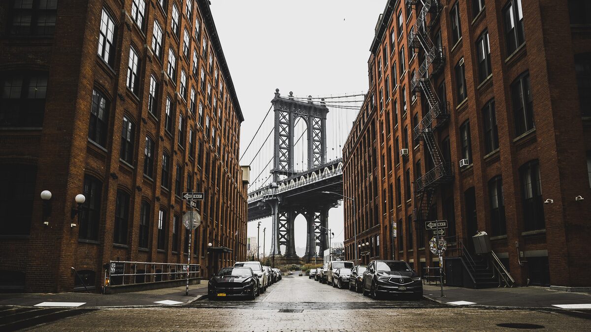 The Manhattan Bridge framed between two brick warehouses at the end of a Dumbo street