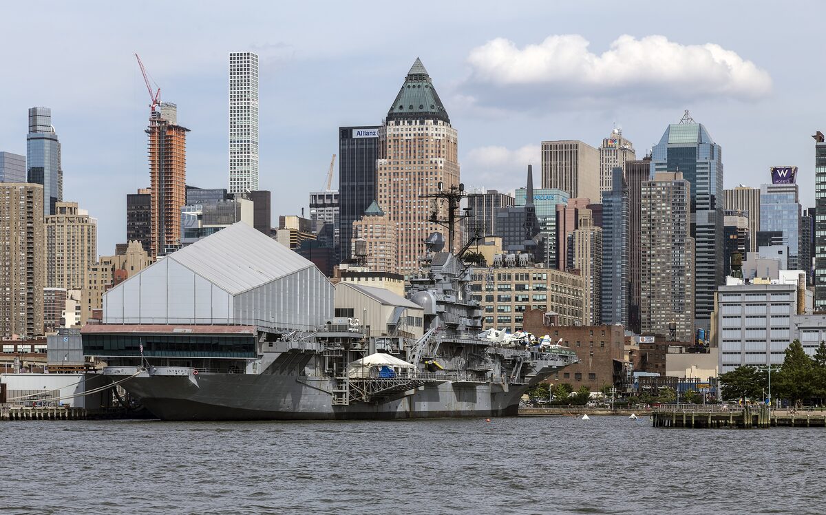 The aircraft carrier Intrepid moored at its Hudson River pier with the Midtown skyline behind