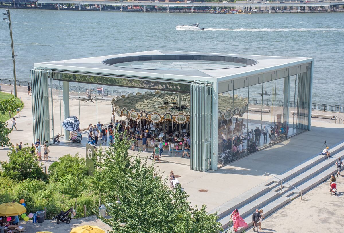 Jane's Carousel inside its glass pavilion on the Brooklyn waterfront, with the East River behind