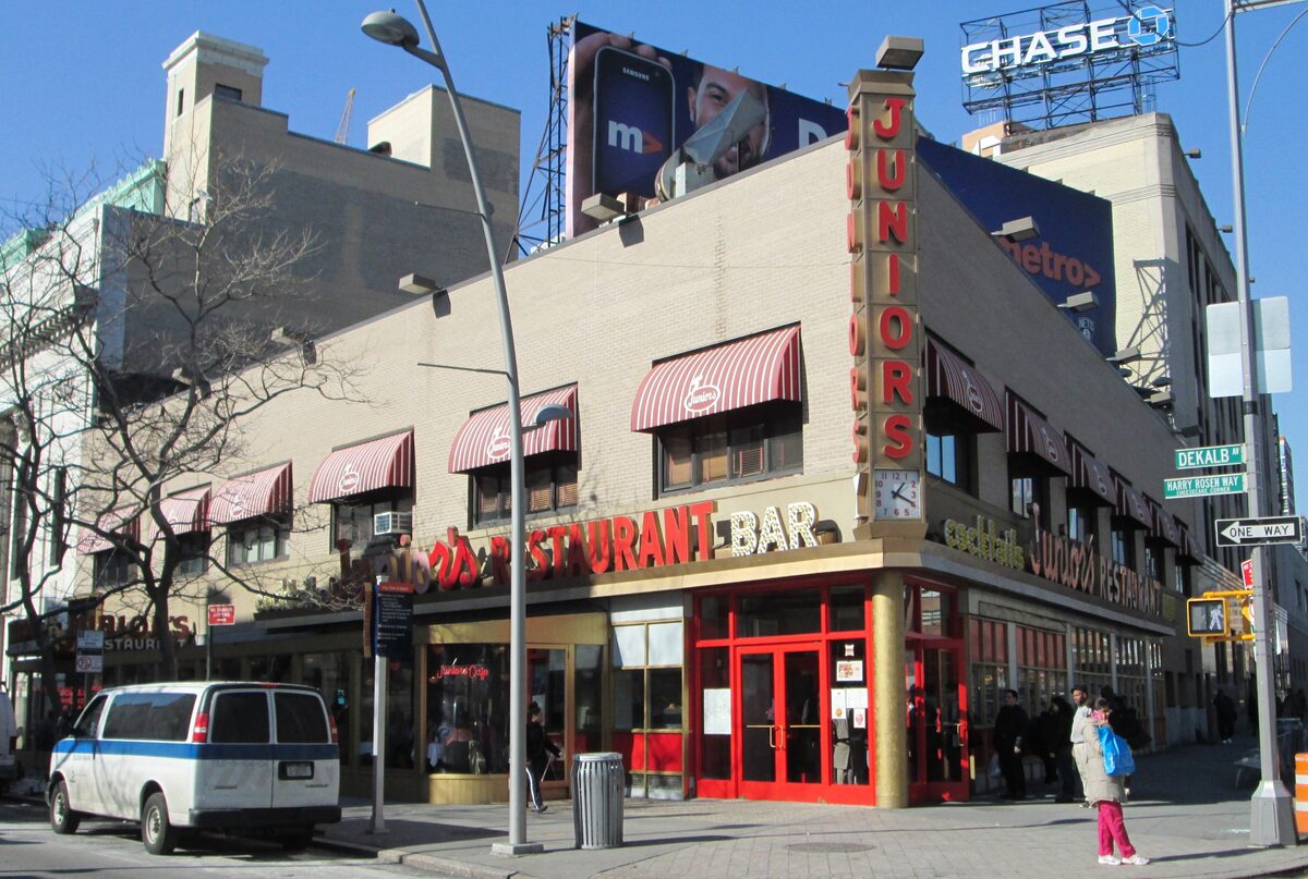 The corner building of Junior's Restaurant in downtown Brooklyn with its red awnings and vertical sign