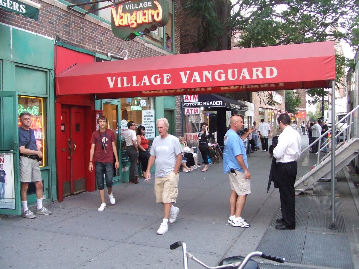 The red Village Vanguard awning and sign over the basement club's entrance on Seventh Avenue South, with passers-by on the sidewalk