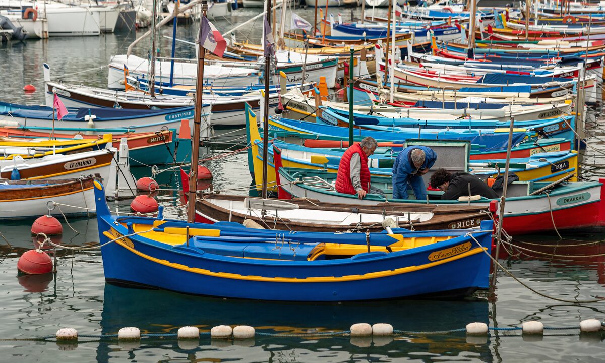 Brightly painted wooden pointu fishing boats moored close together in the port of Nice