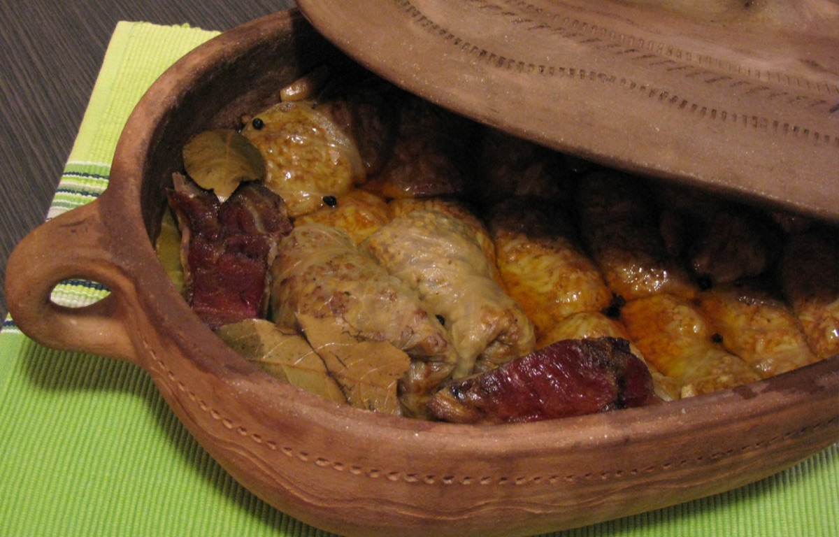 Sarma cabbage rolls and smoked meat in a clay pot with the lid pushed back