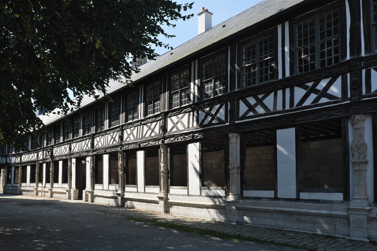 The half-timbered gallery of the Aître Saint-Maclou, its black timber frame and stone columns around the courtyard