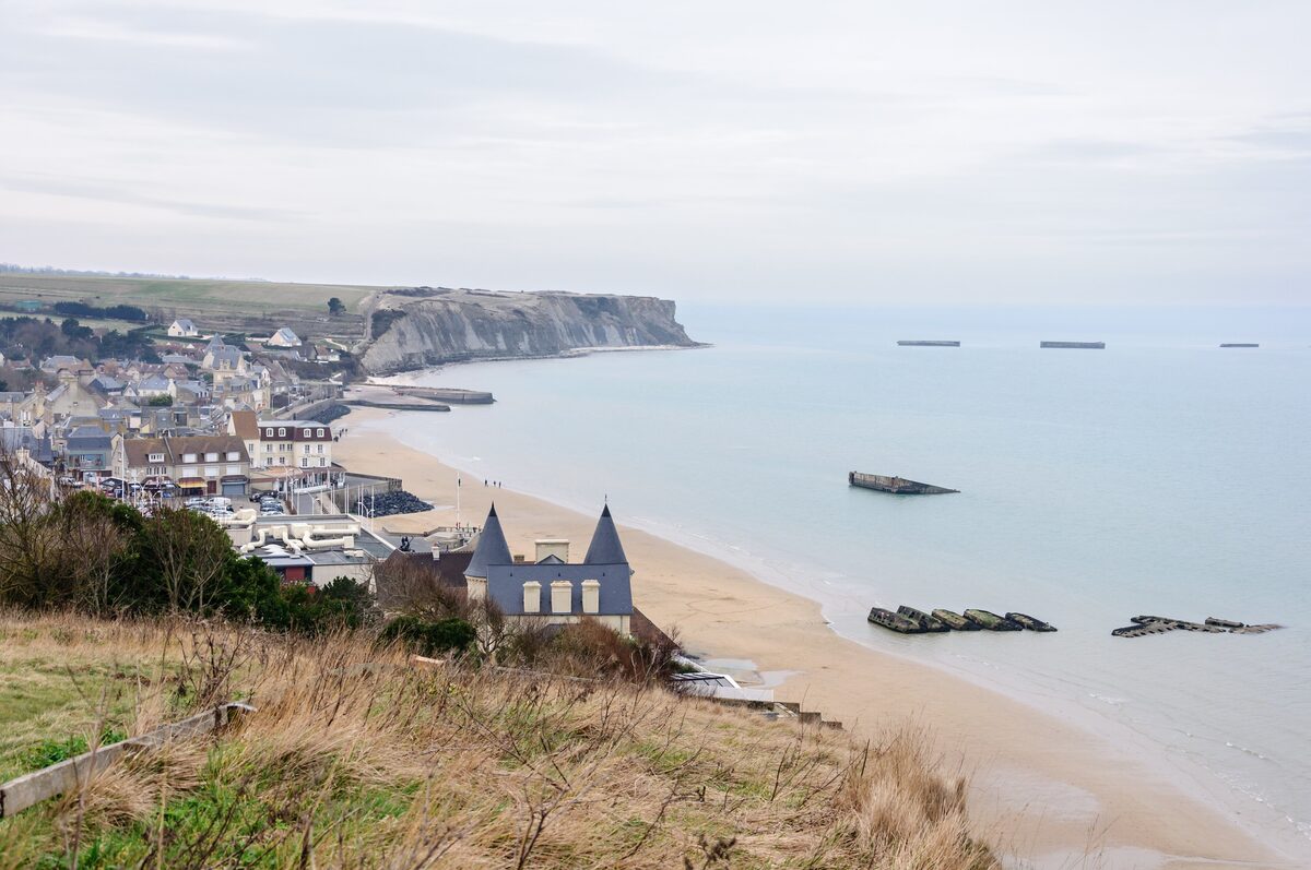 Arromanches seen from the cliff, the town along the bay and the concrete Mulberry harbour caissons in the water