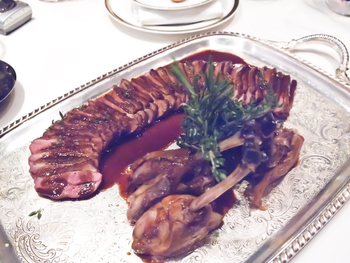Sliced duck breast and legs in a dark red sauce on a silver tray, the Rouen pressed-duck style