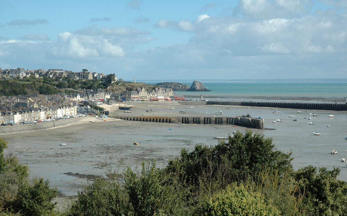 The harbour of Cancale at low tide seen from the hill, with the town along the quay, the stone jetty and small boats on the sand