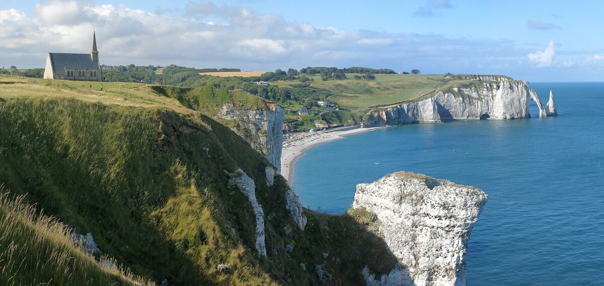 The Notre-Dame-de-la-Garde chapel on the clifftop above Étretat, with the arch and cliffs of the Falaise d'Aval beyond