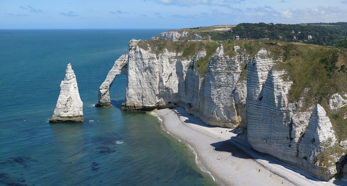 The Aiguille stack and the Porte d'Aval arch in the white cliffs of Étretat, with the pebble beach below