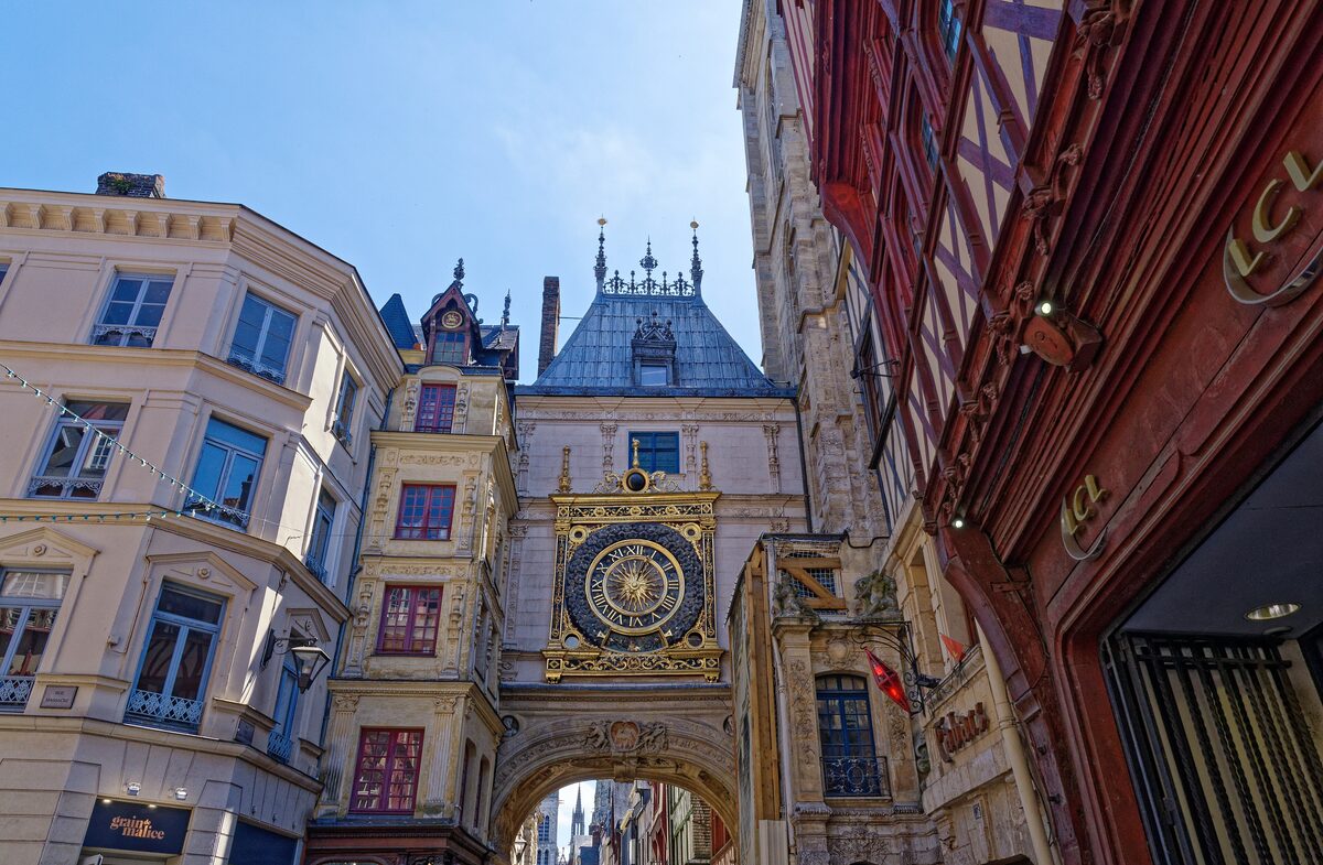 The gilded clock face of the Gros-Horloge set into its belfry arch over the street, with half-timbered houses on both sides