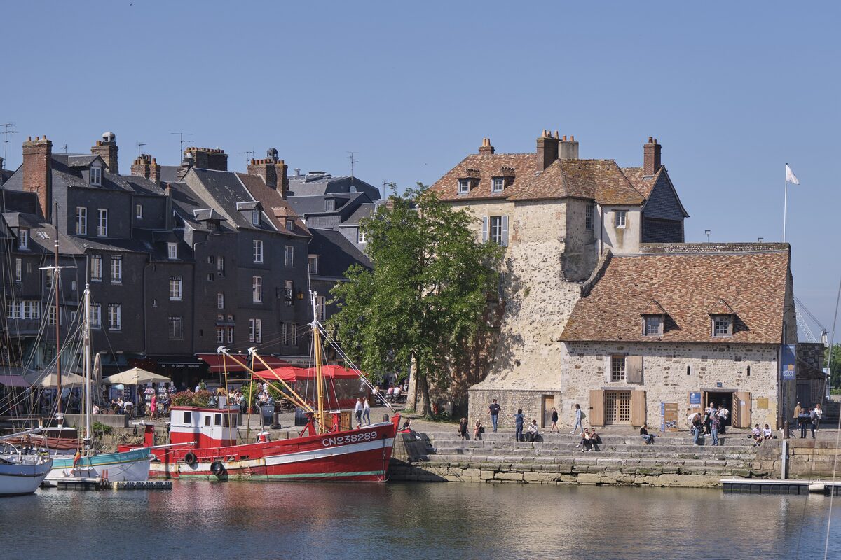 The Lieutenance of Honfleur at the end of the Vieux Bassin, with red fishing boats and the tall slate houses of the quay