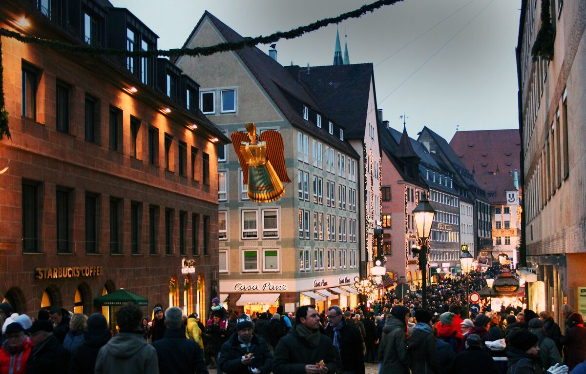 Crowds on a street near the Christkindlesmarkt, with a golden Rauschgoldengel angel hanging overhead