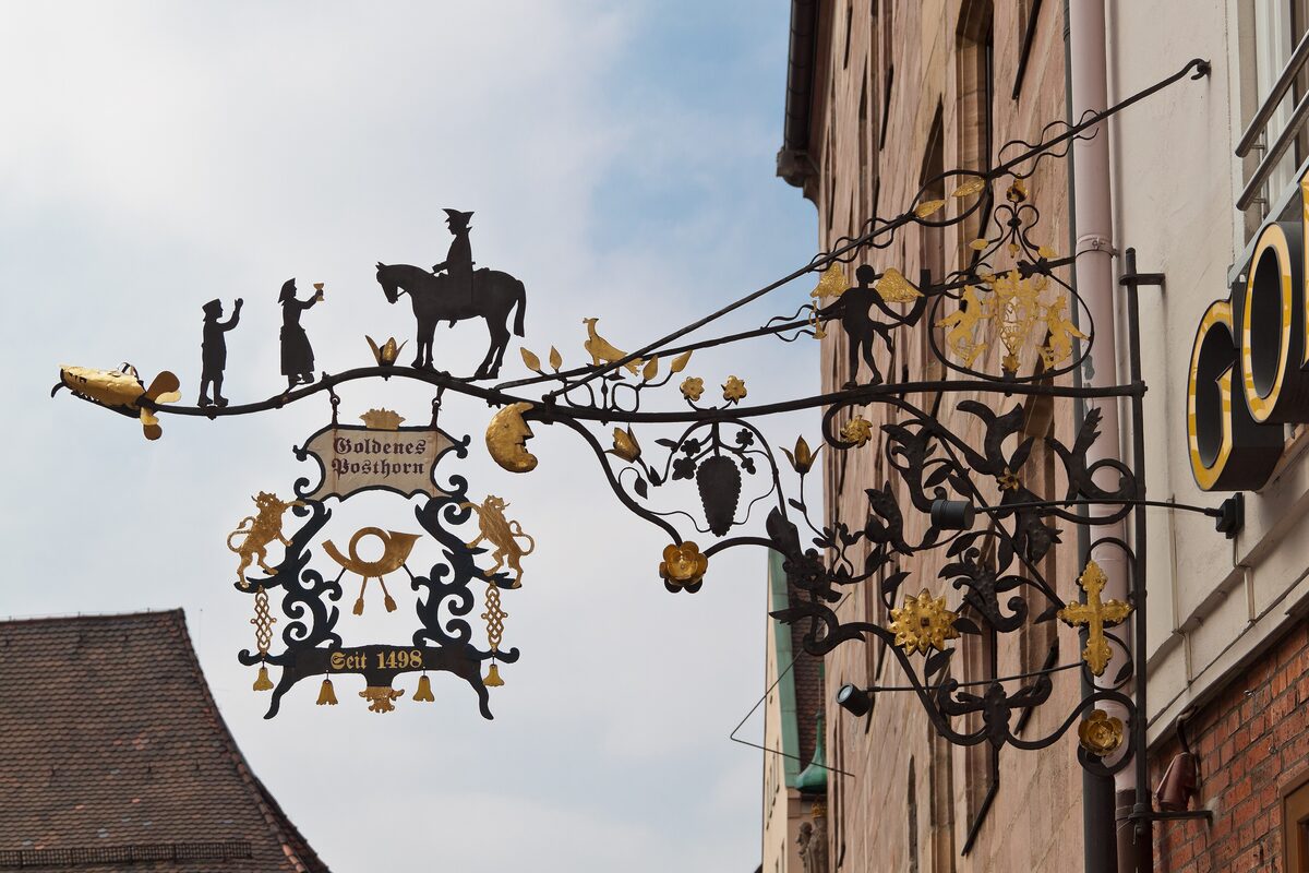 The wrought-iron Goldenes Posthorn sign with a postrider, gilded details and the year 1498