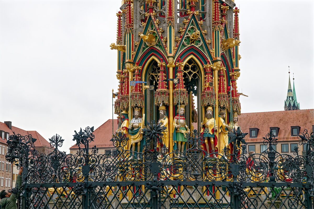 The gilded and painted Schöner Brunnen on the Hauptmarkt behind its iron grille