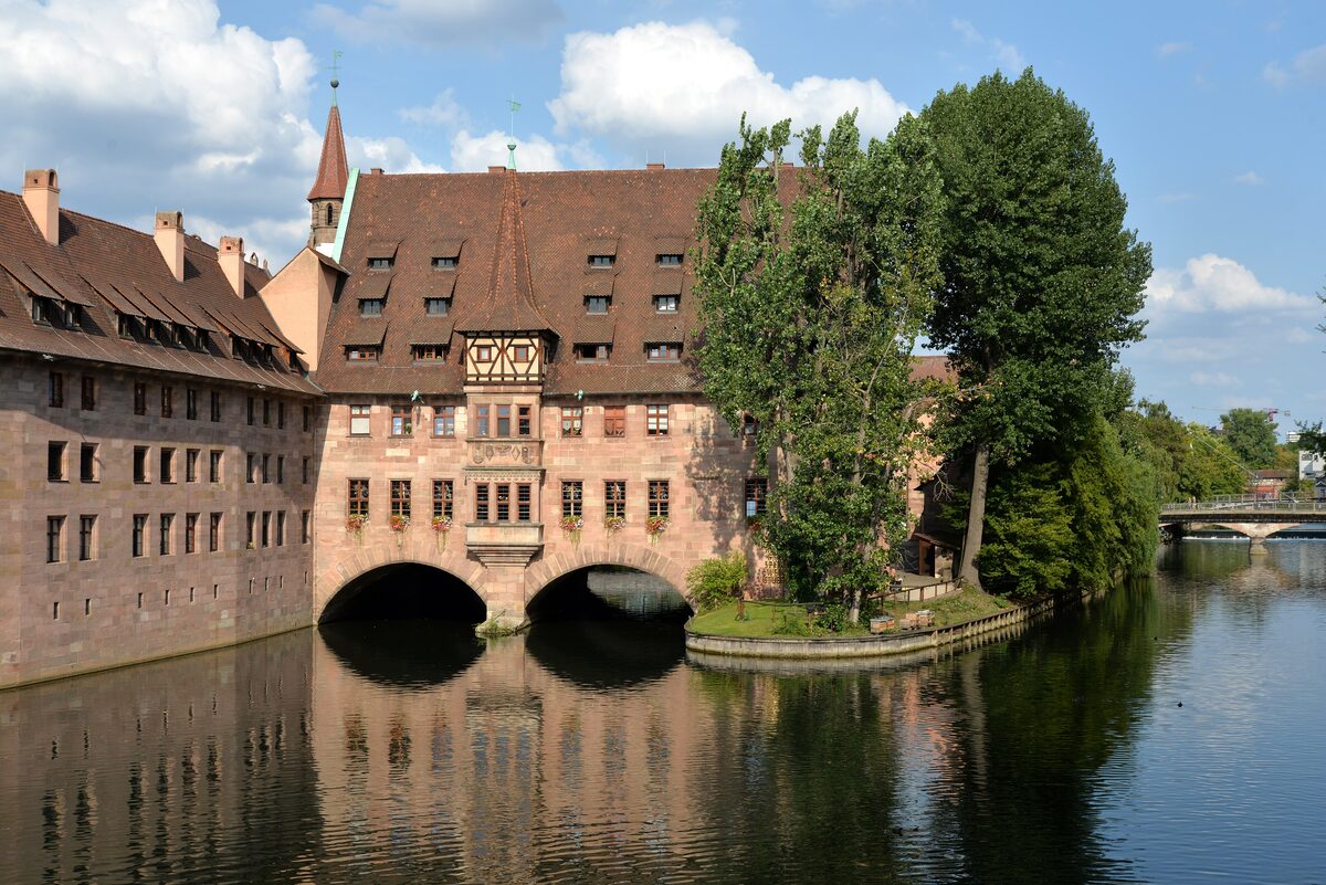 The Heilig-Geist-Spital with its wide arches over the Pegnitz and trees on the bank