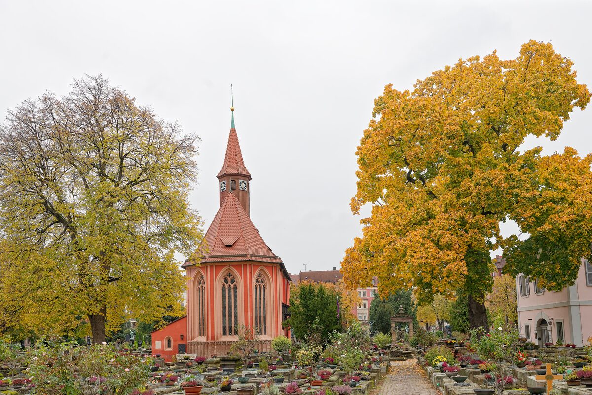 The small red-roofed Johannis chapel among sandstone graves and yellow autumn trees