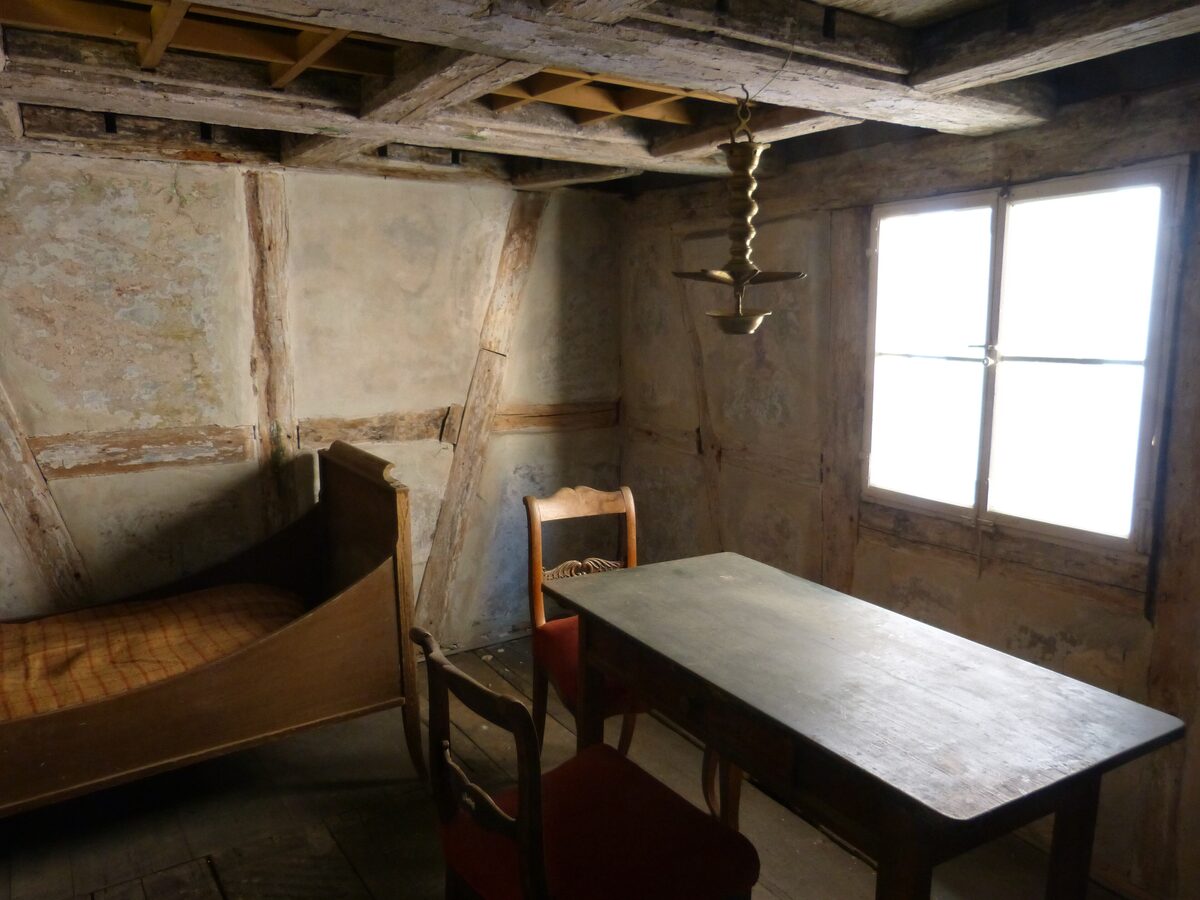 A simple old bed, table and chairs in a timber-framed room in the Jewish Museum Franconia