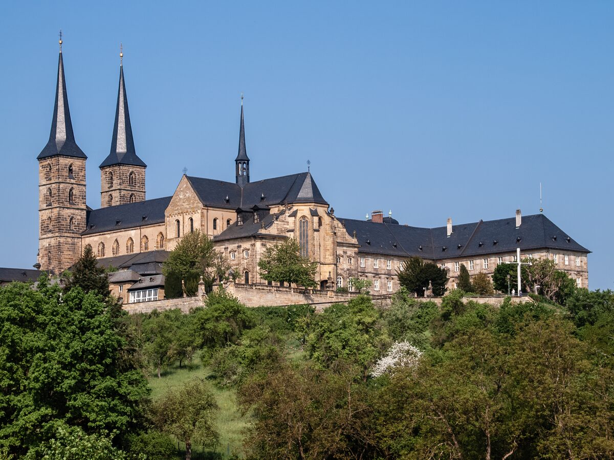 The twin towers and long wings of Michaelsberg Abbey on its hill above green slopes