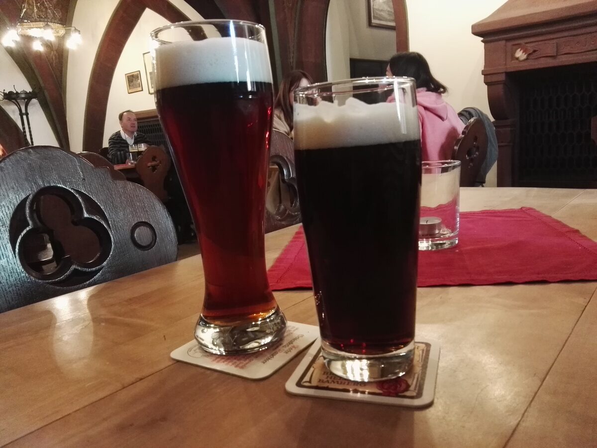 Two glasses of dark Schlenkerla Rauchbier on coasters in a wooden tavern