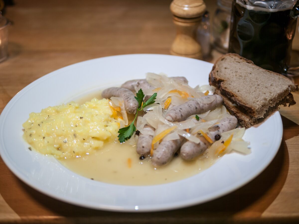 A plate of Saure Zipfel, small sausages in an onion and vinegar broth, with mashed potato and rye bread