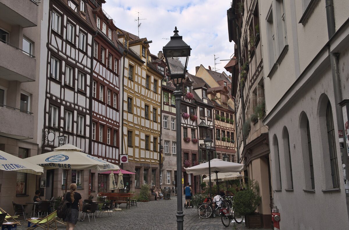 Half-timbered houses along the cobbled Weißgerbergasse with cafe tables and a street lamp