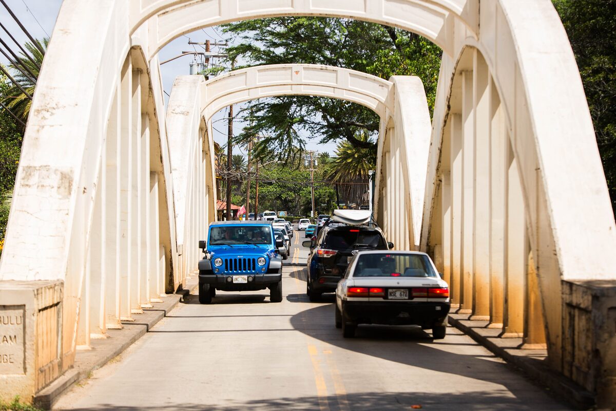 Cars crossing Haleʻiwa's white arched Anahulu bridge on the North Shore