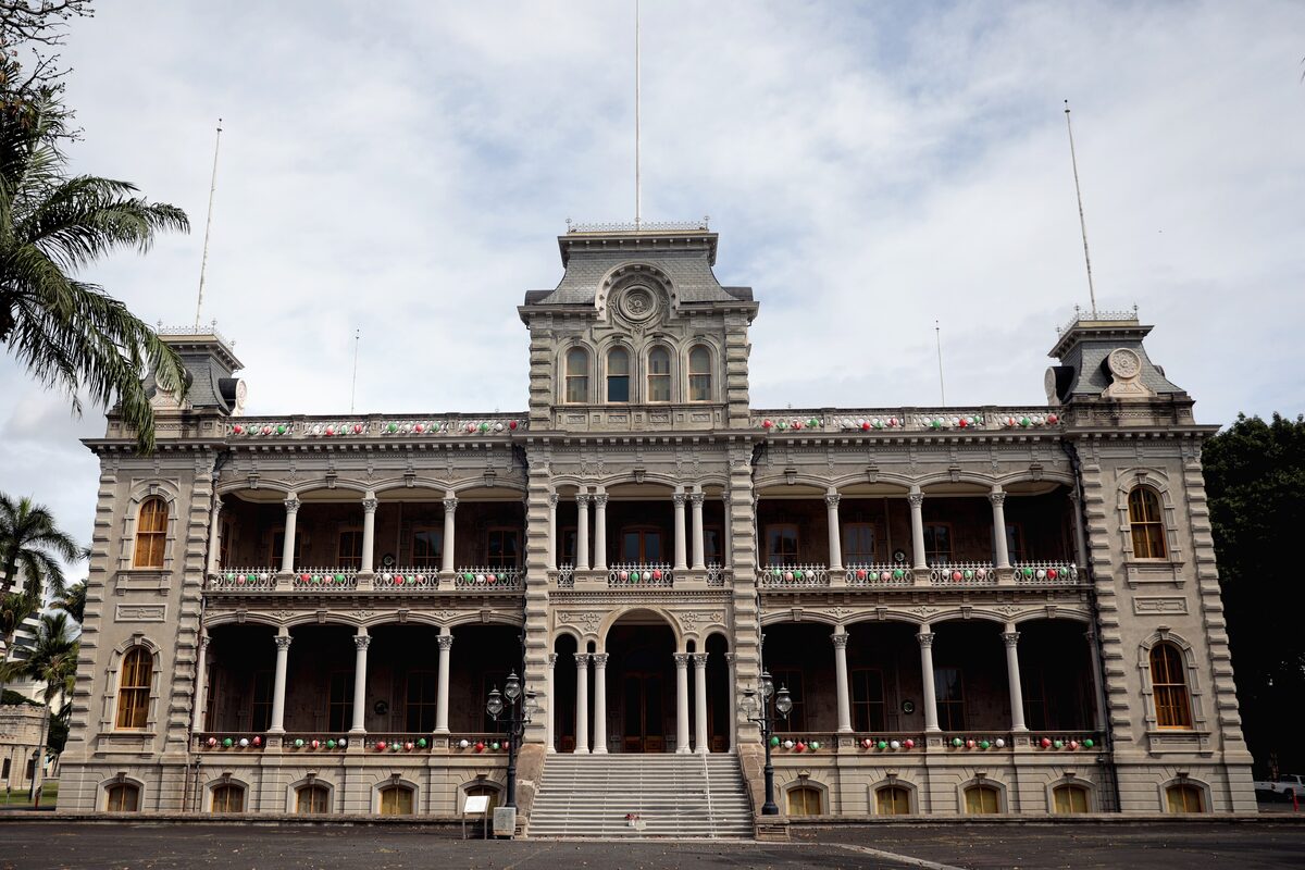 ʻIolani Palace with its two-story verandas and tower behind palm trees