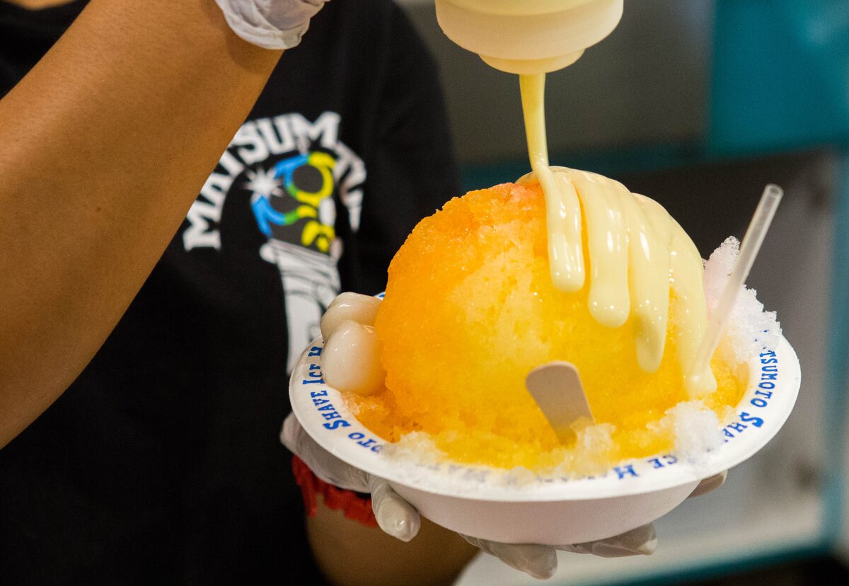 Creamy milk drizzle poured over orange shave ice at Matsumoto