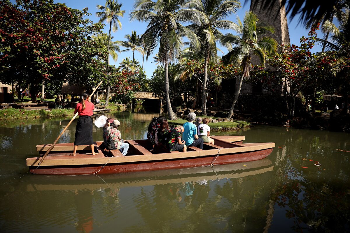 A canoe carrying visitors along the Polynesian Cultural Center's palm-fringed lagoon