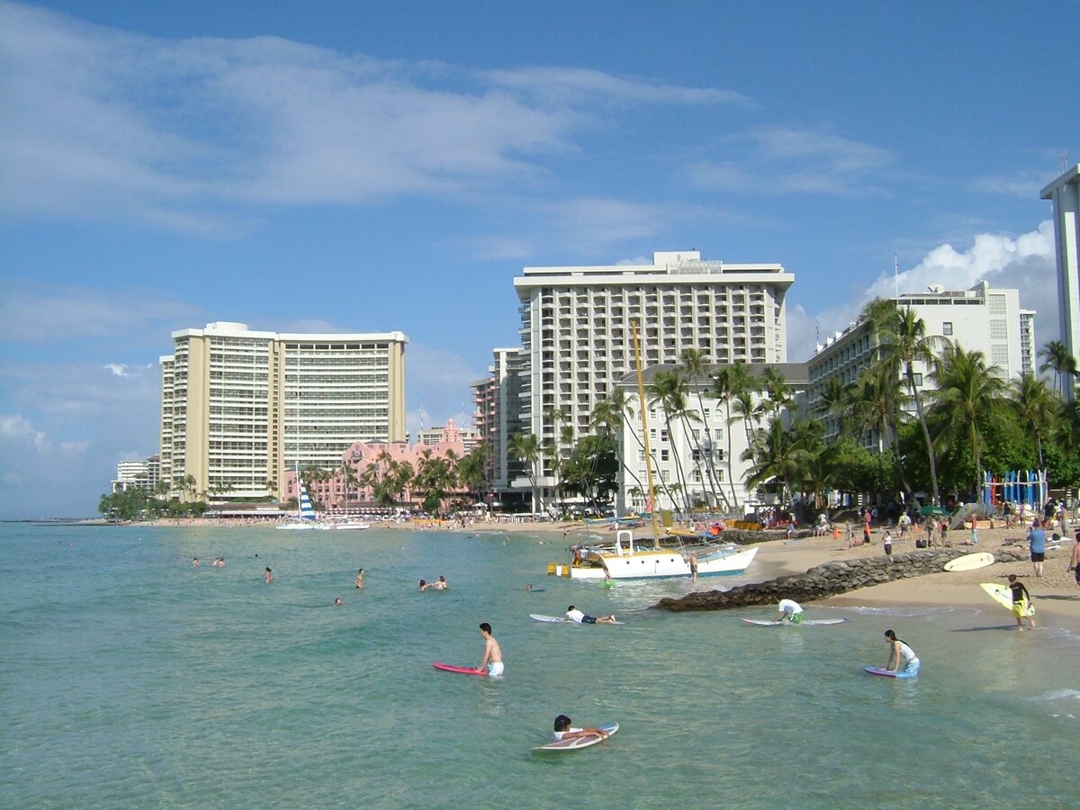 Bodyboarders off Waikīkī's beach with a catamaran and the pink Royal Hawaiian
