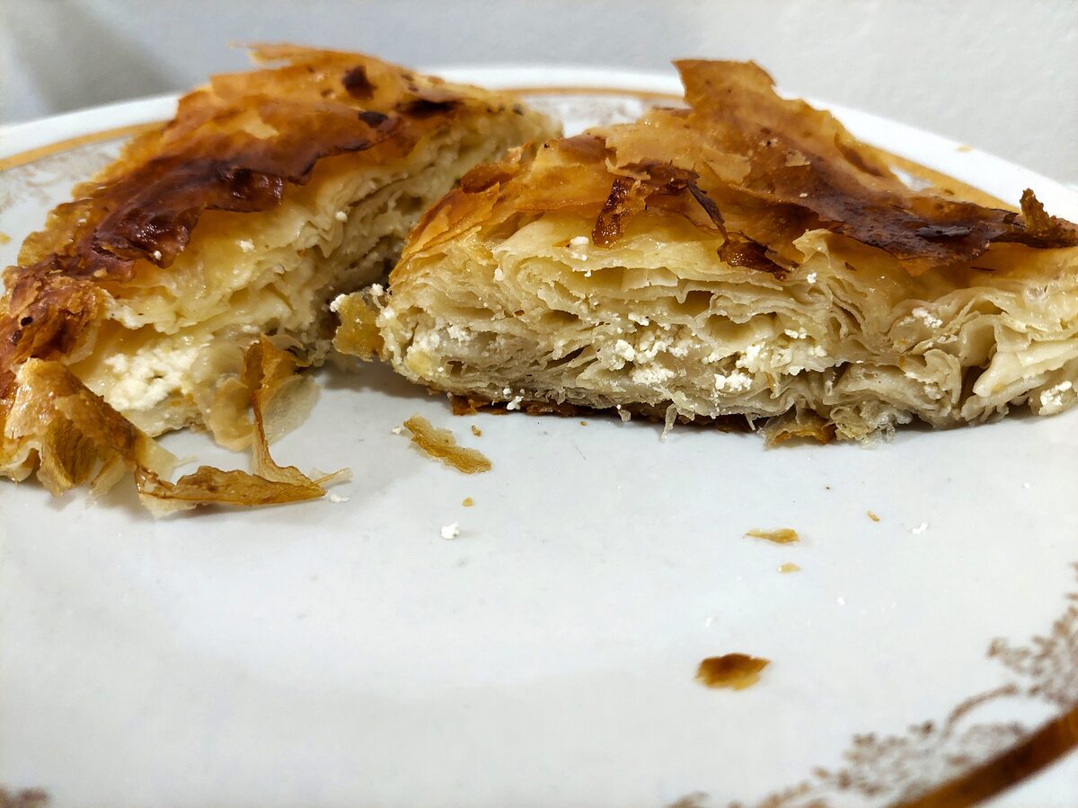 A piece of cheese burek cut open on a plate, showing the flaky golden layers