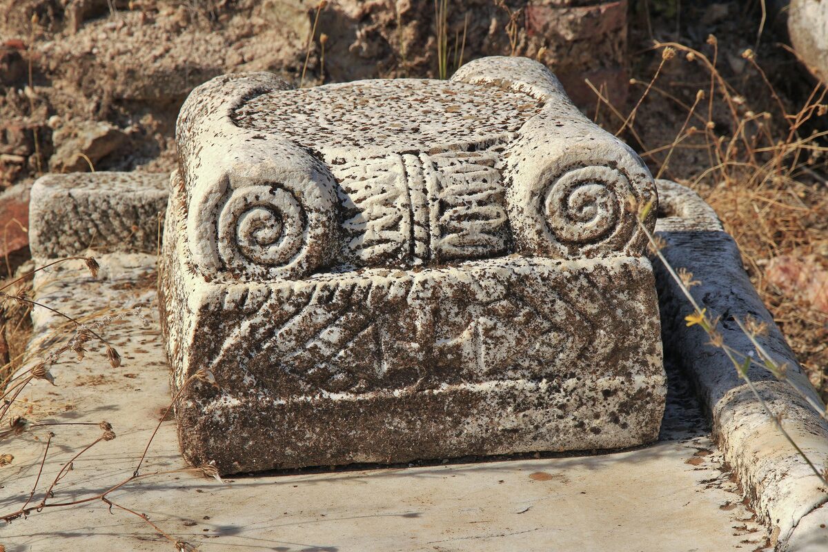 A carved stone capital with spiral volutes lying among the ruins of Heraclea Lyncestis